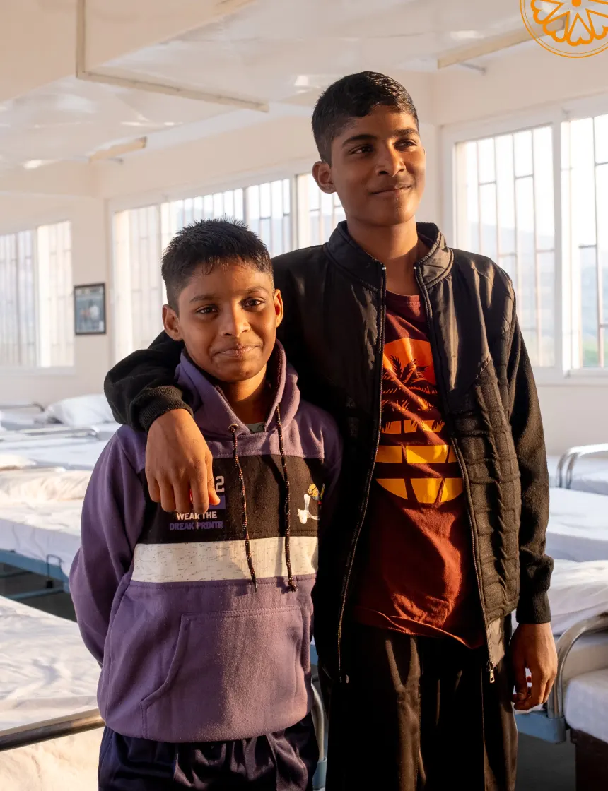 Woman wearing traditional green and red patterned clothing and red bangles.